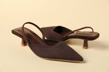 Bej arka planda kahverengi topuklu ayakkabılar, yakın plan.