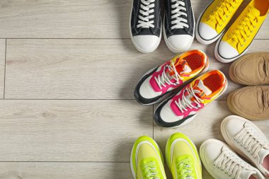 Sportive shoes. Different sneakers on wooden background, flat lay. Space for text