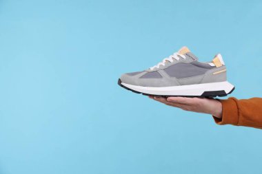 Açık mavi arka planda şık ayakkabılı bir adam, yakın plan. Metin için boşluk