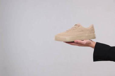 Gri arka planda şık spor ayakkabılı bir adam, yakın plan. Metin için boşluk