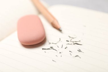 Eraser, pencil and scraps on lined notebook sheet, closeup. Space for text