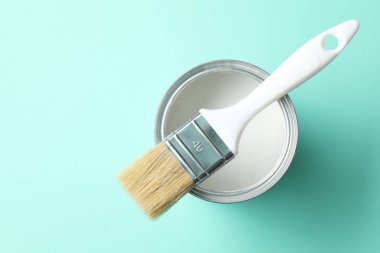 Turkuaz arka planda beyaz boya ve fırça kutusu, üst görünüm