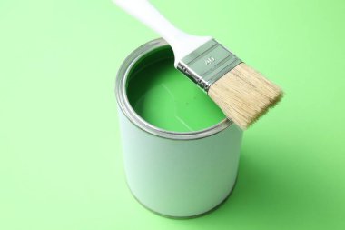 Açık yeşil arka planda parlak boya ve fırça kutusu, yakın plan