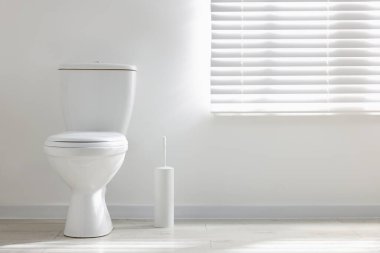 Toilet and brush on floor near white wall