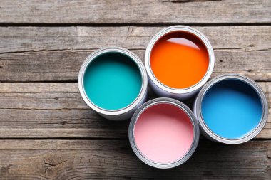 Cans of bright paints on wooden table, flat lay. Space for text