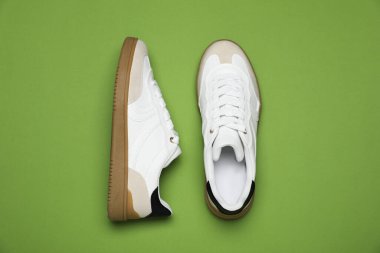 Yeşil arka planda bir çift şık spor ayakkabı, düz. Sıradan ayakkabılar.