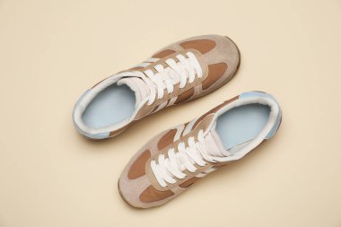 Pair of stylish sneakers on beige background, flat lay. Casual shoes