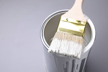 Gri arka planda beyaz boya ve fırça kutusu, yakın plan. Metin için boşluk