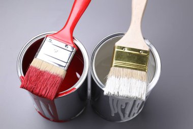 Cans of paint and brushes on grey background, closeup