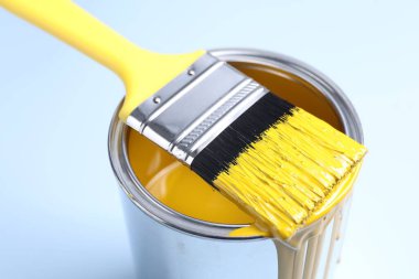 Açık arkaplanda sarı boya ve fırça kutusu, yakın plan.