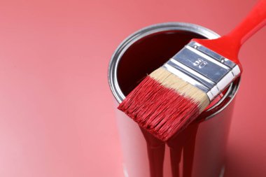 Can of red paint and brush on color background, closeup. Space for text