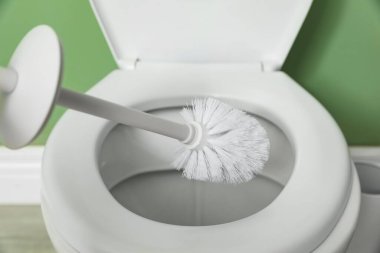 Cleaning toilet bowl with brush indoors, closeup