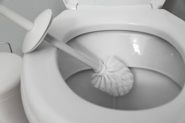 Cleaning toilet bowl with brush indoors, closeup