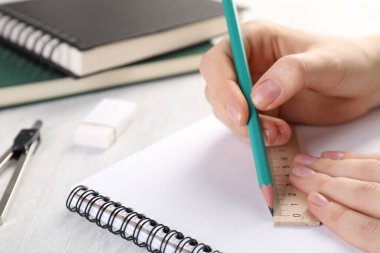 Işık masasında cetvel ve kalemle çizim yapan kadın, yakın plan.