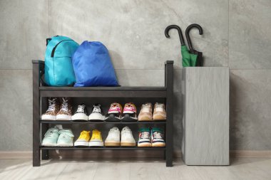 Ayakkabı bankı, farklı ayakkabılar, sırt çantası, spor çantası ve şemsiyeler.