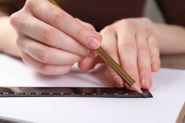 Masada cetvel ve kalemle çizim yapan kadın, yakın plan.