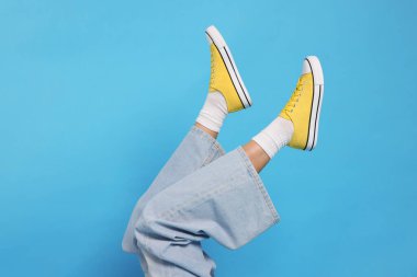 Açık mavi arka planda şık ayakkabılar giyen kadın, yakın plan.