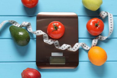 Elektronik mutfak ölçeği, mezura ve açık mavi ahşap masa üzerindeki ürünler, düz yatak. Diyet