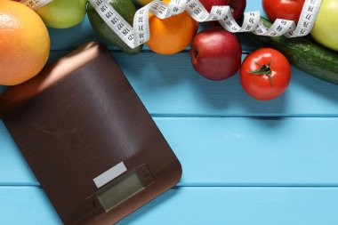 Elektronik mutfak ölçeği, mezura ve açık mavi ahşap masa üzerindeki ürünler, düz yatak. Diyet