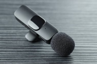 Lavalier mikrofonu siyah ahşap masada, yakın plan.