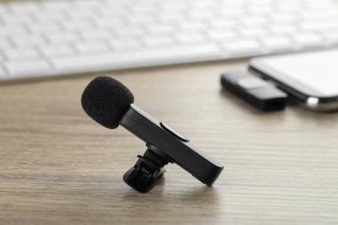 Lavalier mikrofon ve ahşap masada kablosuz alıcısı olan akıllı telefon.