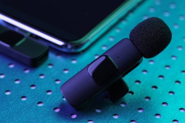 Lavalier mikrofon ve kablosuz alıcısı neon lambalı akıllı telefon, yakın plan.