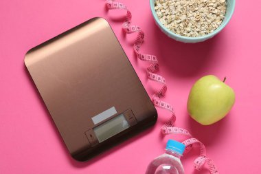 Elektronik mutfak ölçeği, mezura ve pembe arka plandaki ürünler, düz konum. Diyet