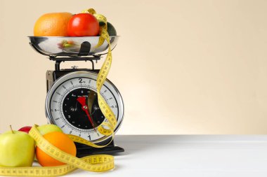 Mutfak terazisinde bir kase ürün ve bej arka planda beyaz ahşap masada şerit var. Metin için boşluk