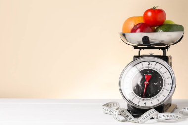 Mutfak terazisinde bir kase ürün ve bej arka planda beyaz ahşap masada şerit var. Metin için boşluk