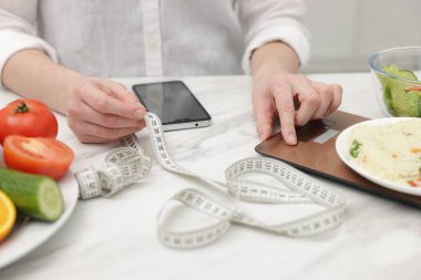 Beyaz masada risotto ağırlığında akıllı telefonlu bir kadın, yakın plan.