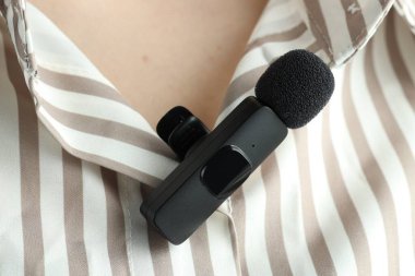 Gömleğinde lavalier mikrofon olan bir kadın, yakın plan.