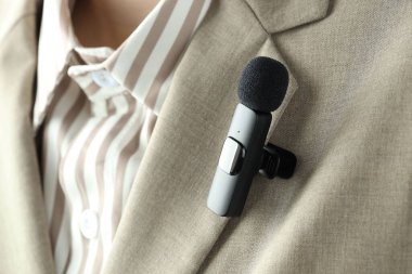 Gömleğinde lavalier mikrofon olan bir kadın, yakın plan.