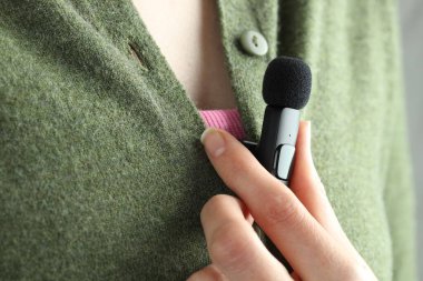 Kadın gömleğine mikrofon takıyor, yakın plan.