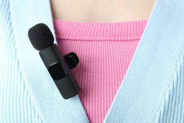 Gömleğinde lavalier mikrofon olan bir kadın, yakın plan.