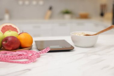 Mutfak pulları, meyveler, yulaf ezmesi ve beyaz mermer masa üzerindeki mezura, yakın plan.