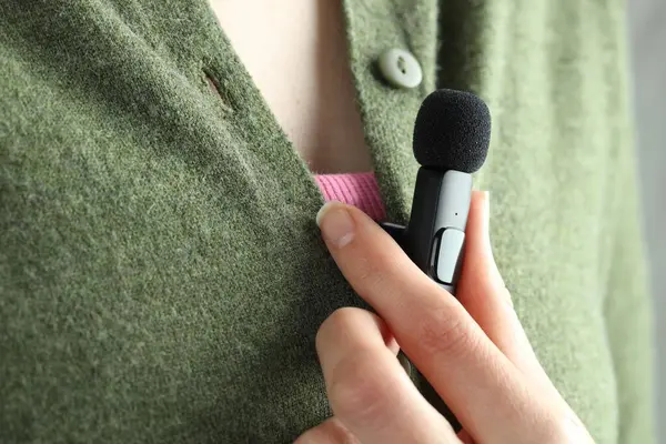 Kadın gömleğine mikrofon takıyor, yakın plan.