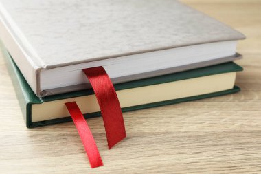 Açık ahşap masa üzerinde kırmızı kurdele yer imleri olan kitaplar, yakın plan