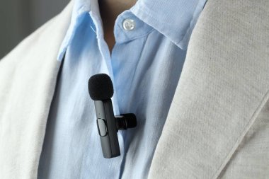 Gömleğine mikrofon takmış bir adam, yakın plan.