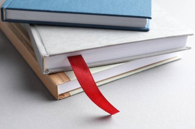 Açık gri masadaki renkli olanlar arasında kırmızı kurdele yer imi olan kitap, yakın plan