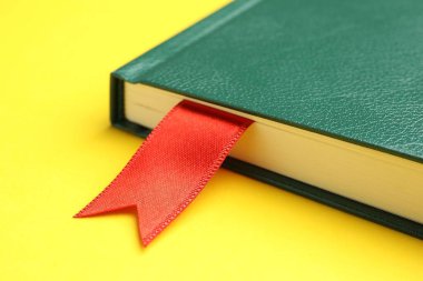 Sarı arkaplanda kırmızı kurdele yer imi olan kitap, yakın plan