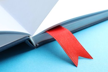 Açık mavi arkaplanda kırmızı kurdele yer imi olan kitap, yakın plan