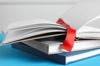 Kırmızı kurdele yer imi ve açık mavi arka planda renkli kitap, yakın plan
