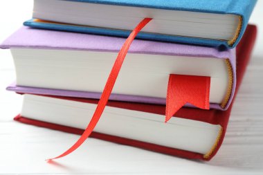 Beyaz ahşap masa üzerinde kırmızı kurdele yer imleri olan kitaplar, yakın plan