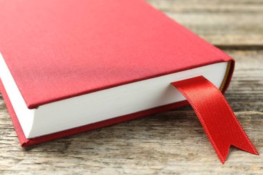 Ahşap masada kırmızı kurdele yer imi olan bir kitap, yakın plan.
