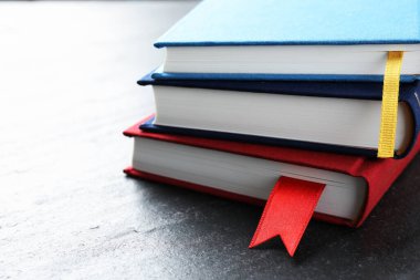 Koyu desenli masa üzerinde kırmızı kurdele yer imleri olan kitaplar, yakın plan