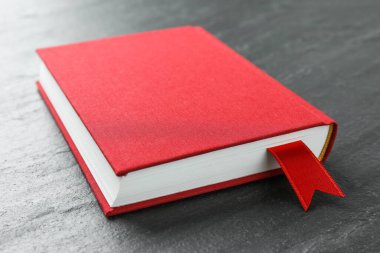 Koyu desenli masa üzerinde kırmızı kurdele yer imi olan kitap, yakın plan.