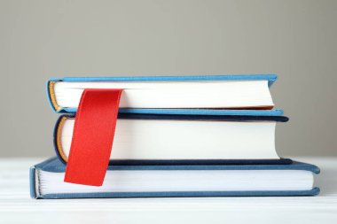 Kırmızı kurdele yer imi ve beyaz ahşap masa üzerinde renkli kitap gri arkaplan, yakın plan