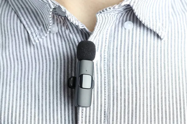 Gömleğine mikrofon takmış bir adam, yakın plan.