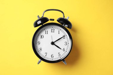 Sarı zemin üzerinde siyah alarm saati, üst görünüm