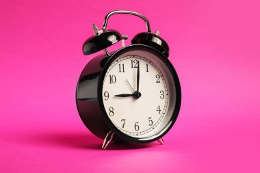 Parlak pembe arkaplanda siyah bir çalar saat